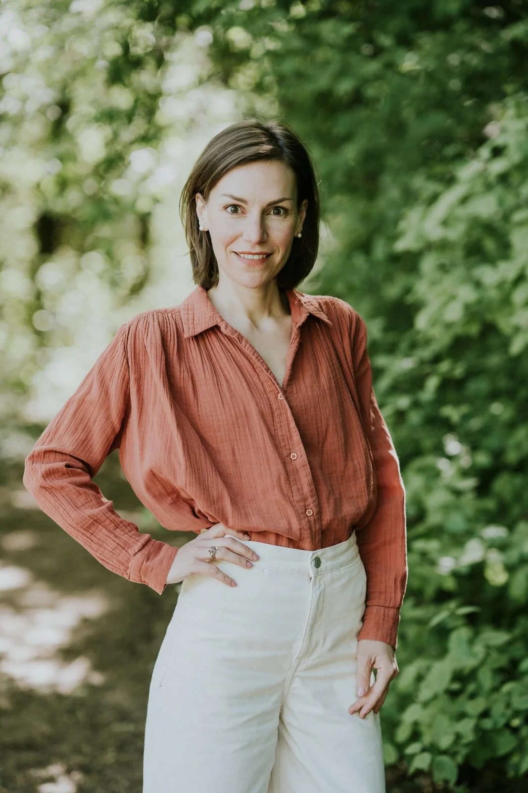 Aude, chemise terracotta, devant un feuillage